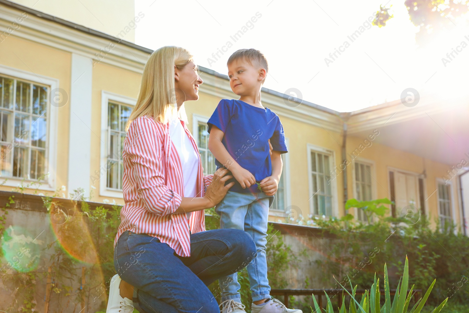 Photo of Nanny with cute little boy outdoors on sunny day, low angle view