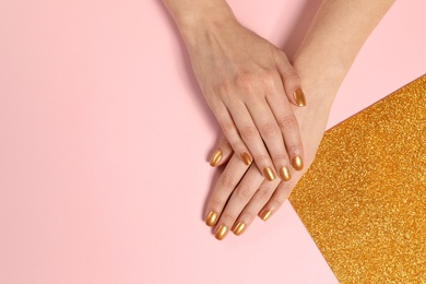 Photo of Woman showing manicured hands with golden nail polish on color background, top view. Space for text