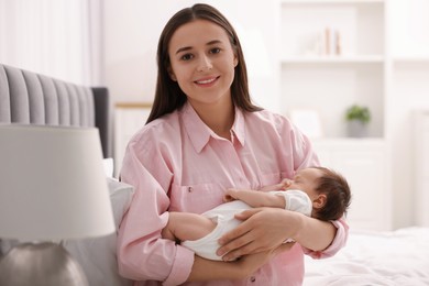 Mother with her sleeping newborn baby on bed at home