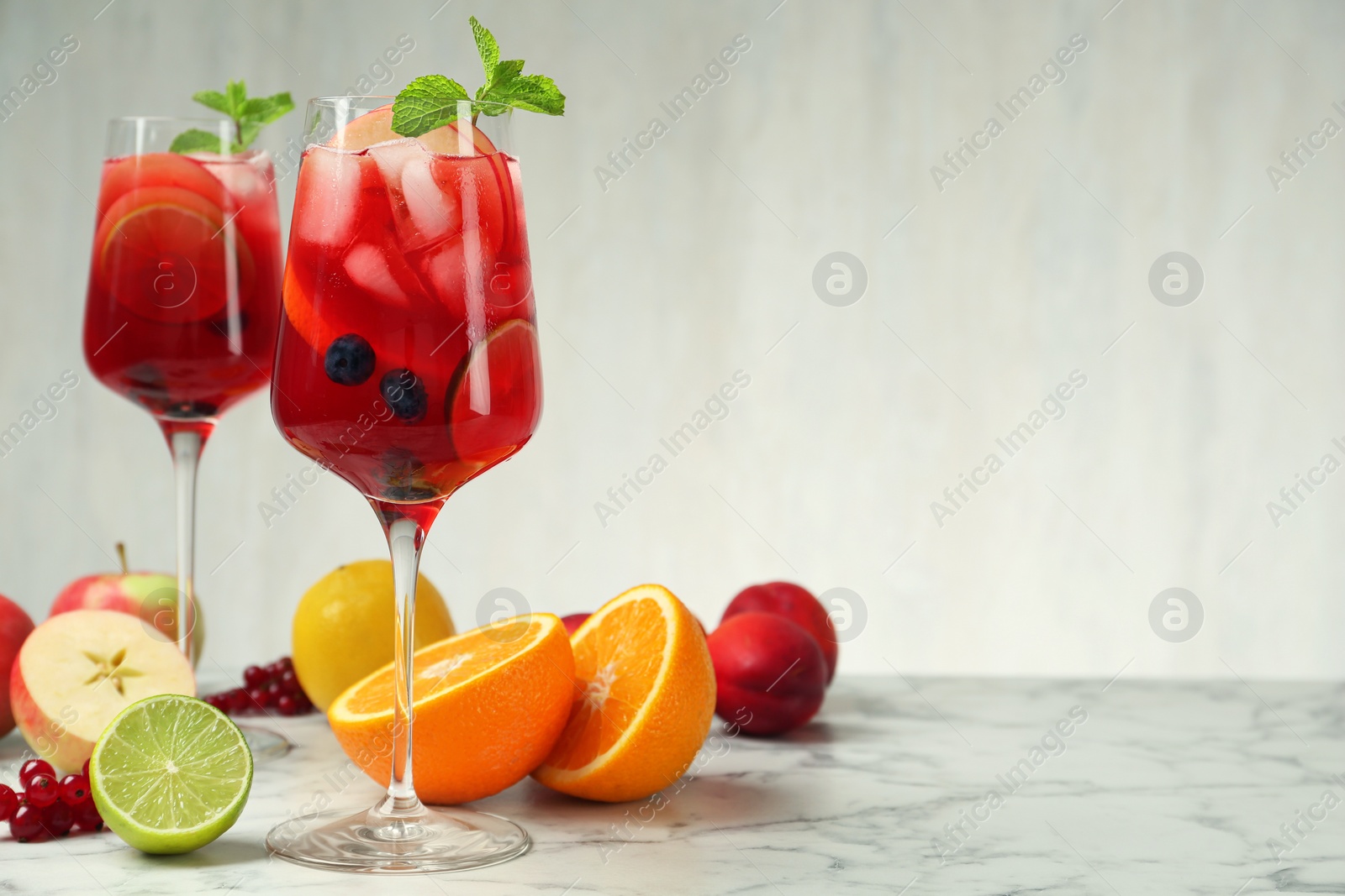 Photo of Delicious Red Sangria and fruits on white marble table, space for text