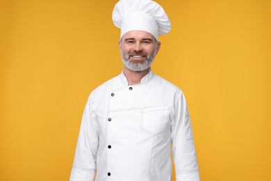 Photo of Happy chef in uniform on orange background