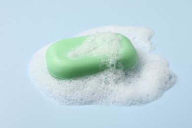 Photo of Soap and fluffy foam on light blue background