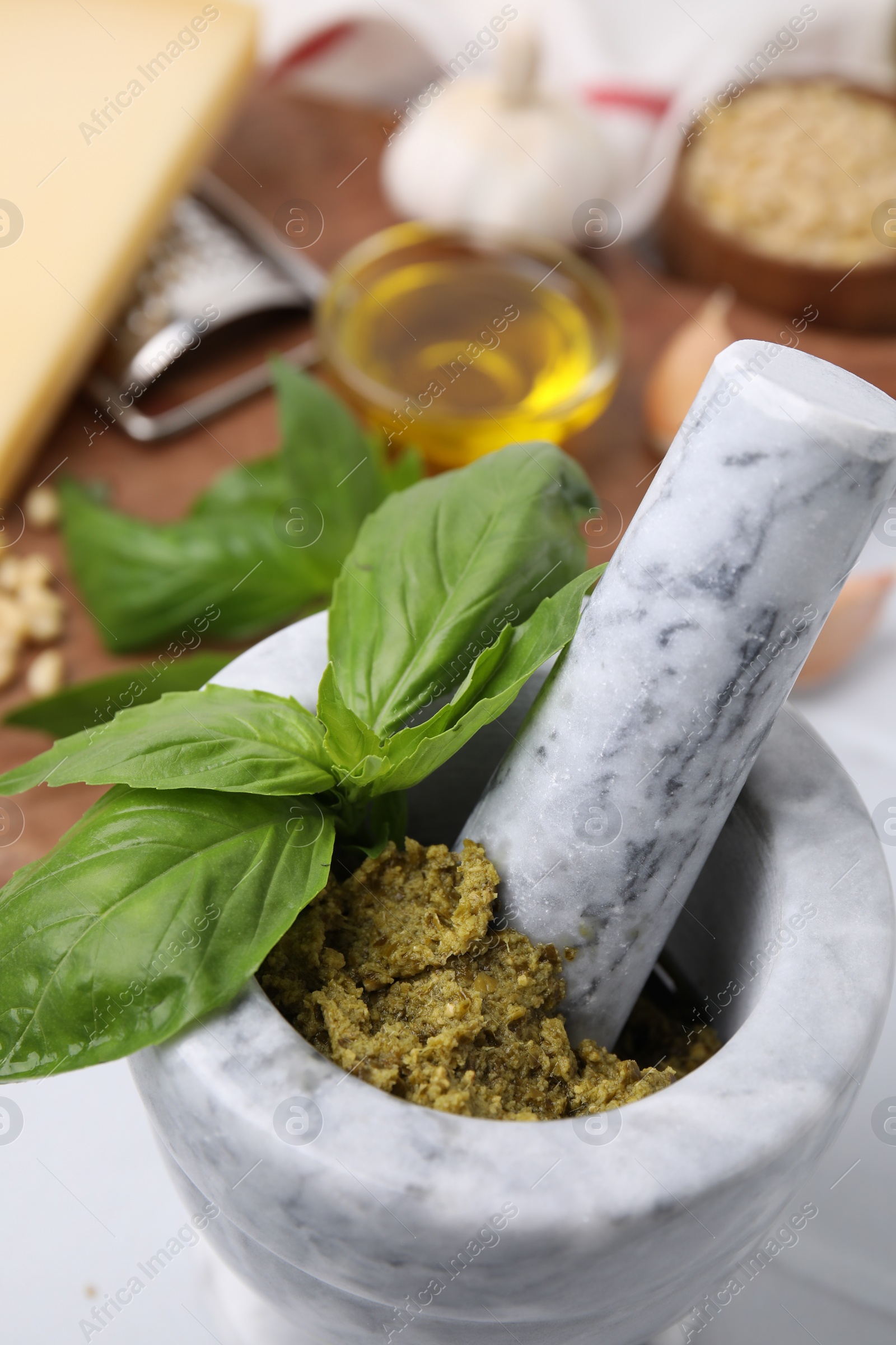 Photo of Tasty pesto sauce and fresh basil in mortar, closeup