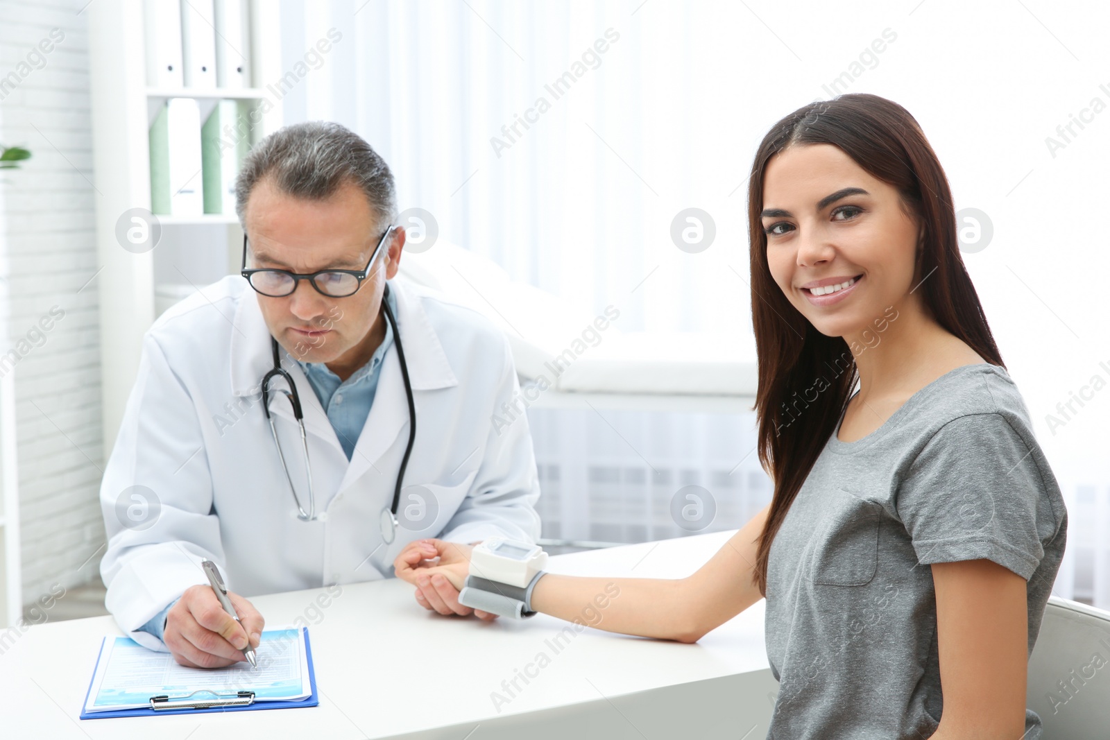 Photo of Doctor checking young woman's pulse with medical device in hospital