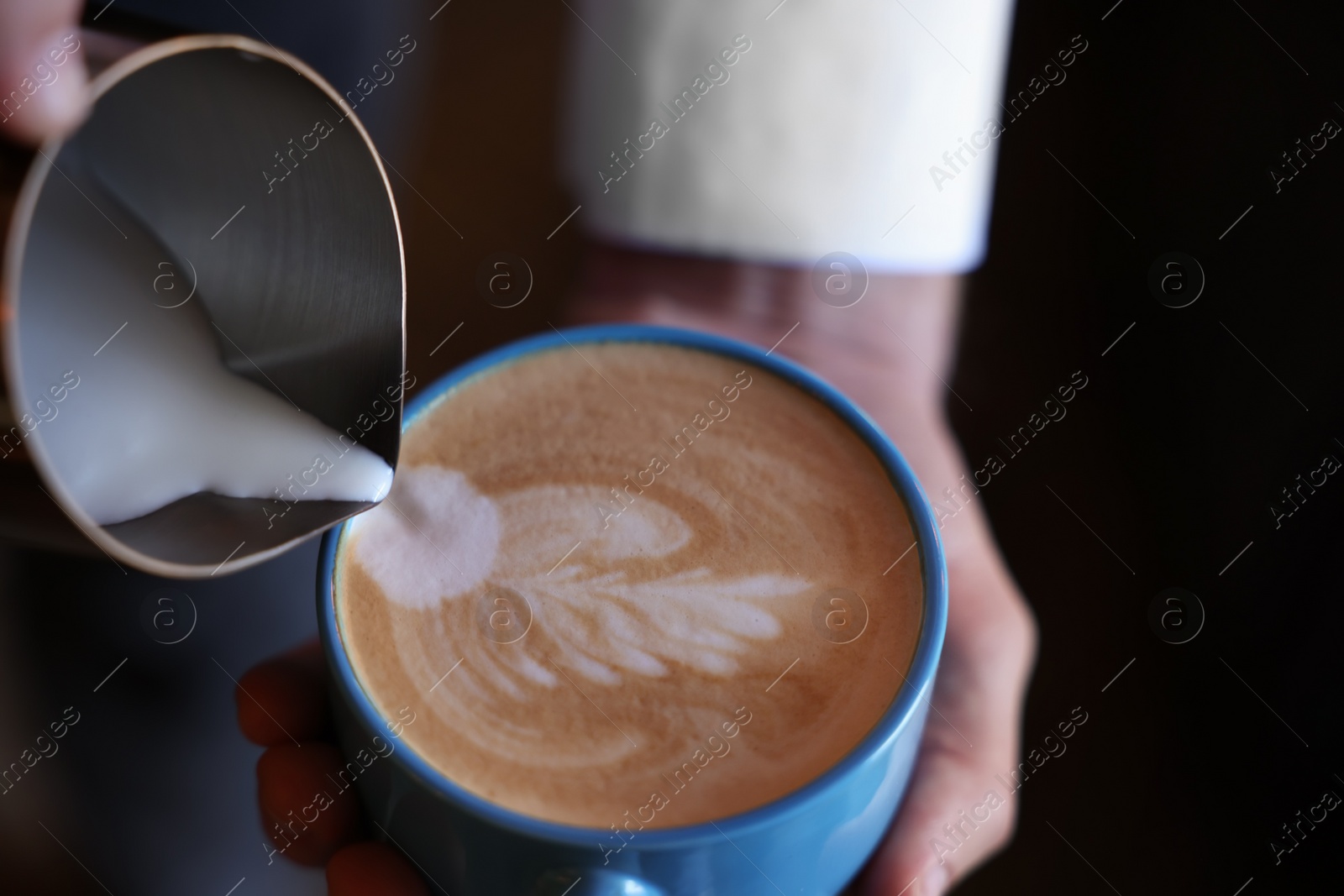 Photo of Barista pouring milk into cup of coffee on black background, closeup. Space for text