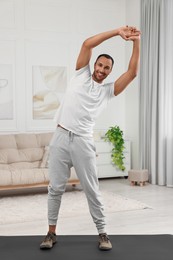 Photo of Man doing morning exercise on fitness mat at home