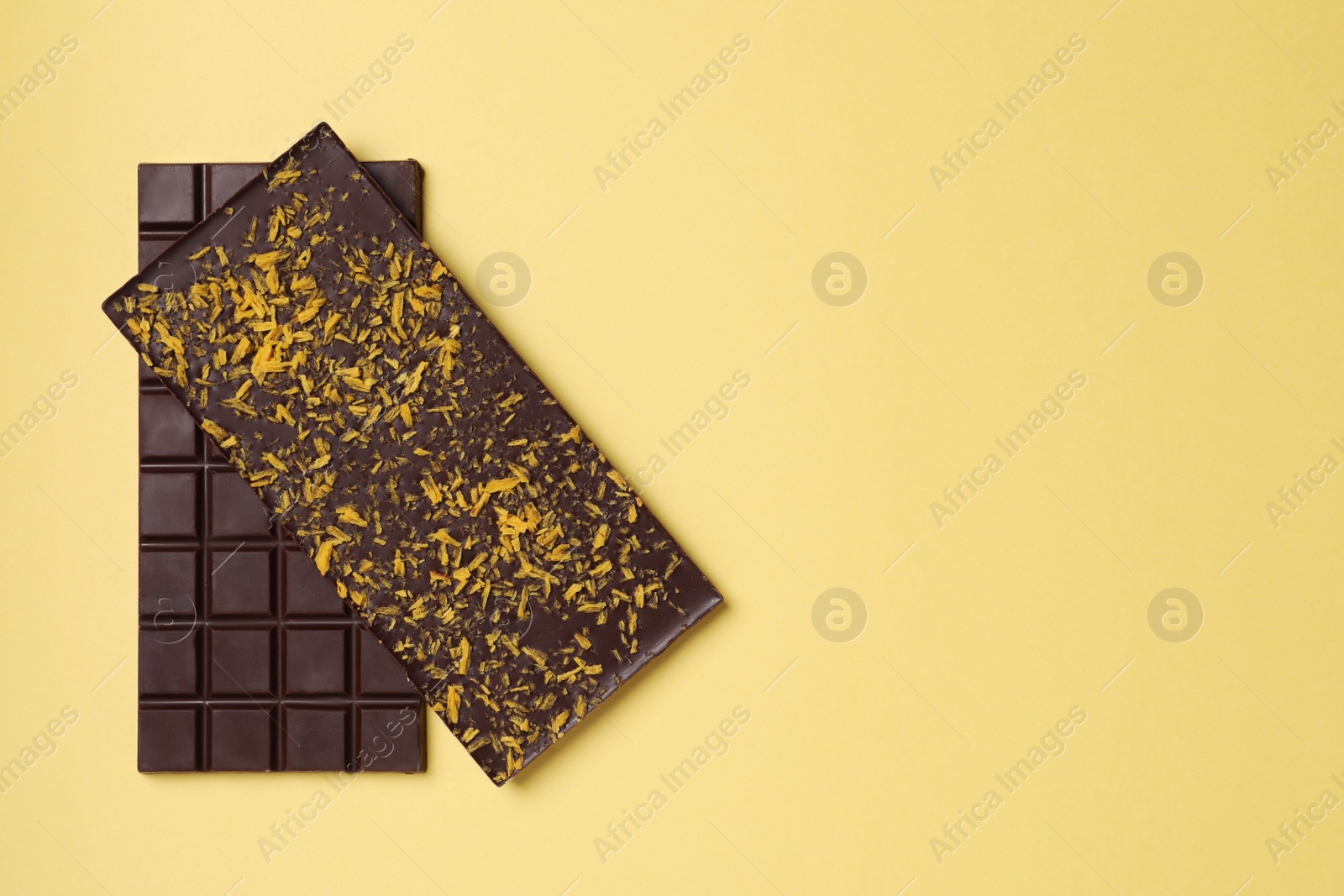 Photo of Chocolate bars with freeze dried fruits on yellow background, top view. Space for text