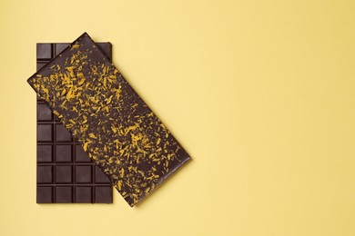 Photo of Chocolate bars with freeze dried fruits on yellow background, top view. Space for text