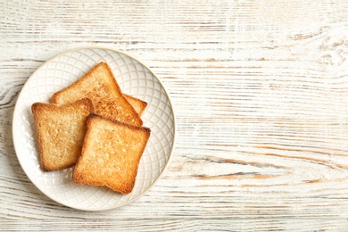 Photo of Plate with toasted bread on wooden background, top view