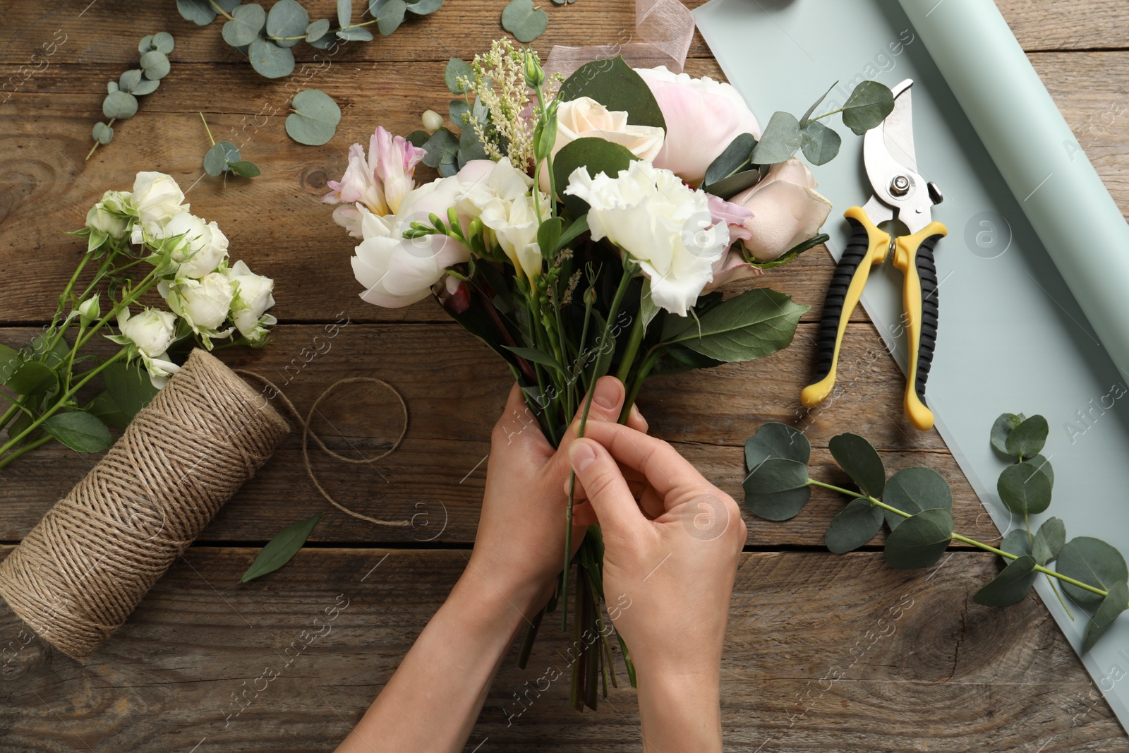 Photo of Florist creating beautiful bouquet at table, top view