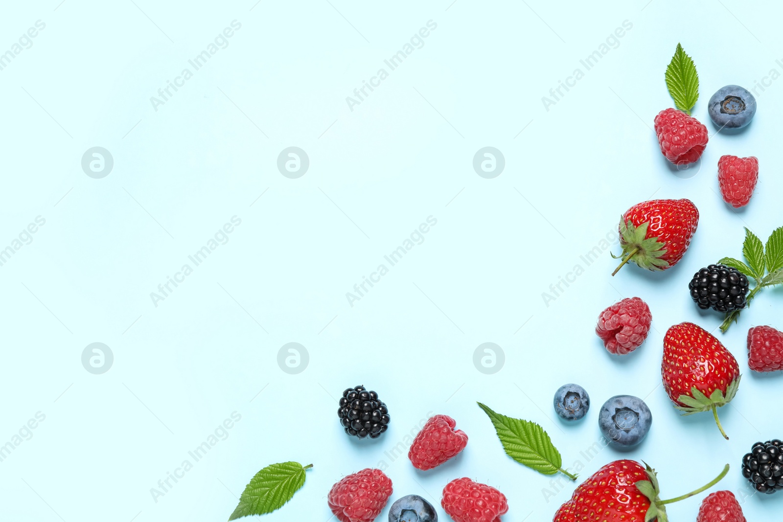 Photo of Different fresh berries on light blue background, flat lay. Space for text