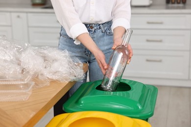 Woman separating garbage at table indoors, closeup