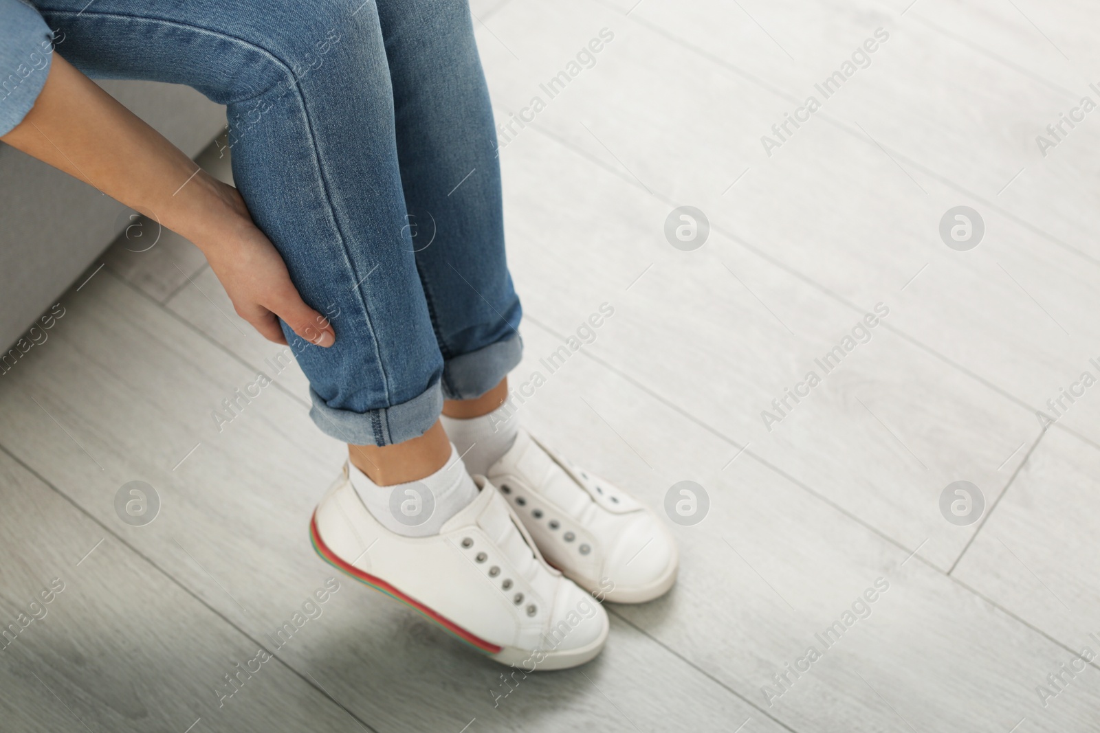 Photo of Young woman suffering from leg pain indoors, closeup with space for text