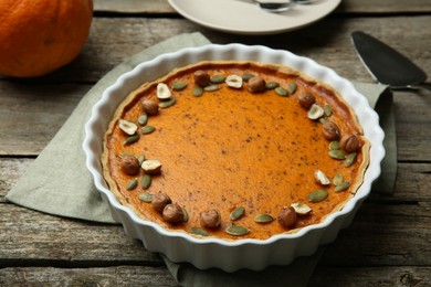 Photo of Delicious pumpkin pie with seeds and hazelnuts on wooden table