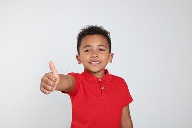 Photo of African-American boy showing thumb up on light grey background