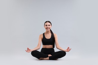 Photo of Beautiful young woman practicing yoga on grey background. Lotus pose
