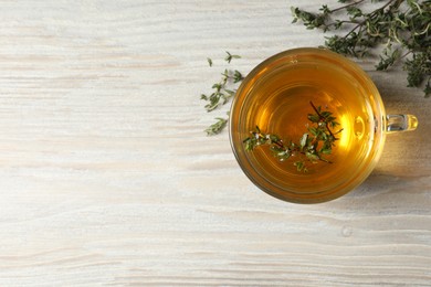 Photo of Cup of fresh thyme tea on wooden table, flat lay. Space for text