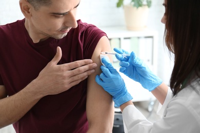 Photo of Doctor vaccinating male patient in clinic