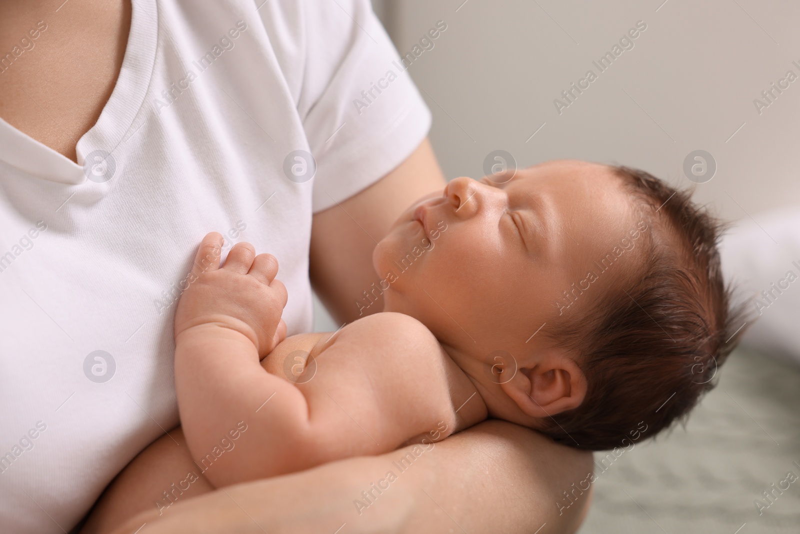 Photo of Mother holding her cute newborn baby indoors, closeup