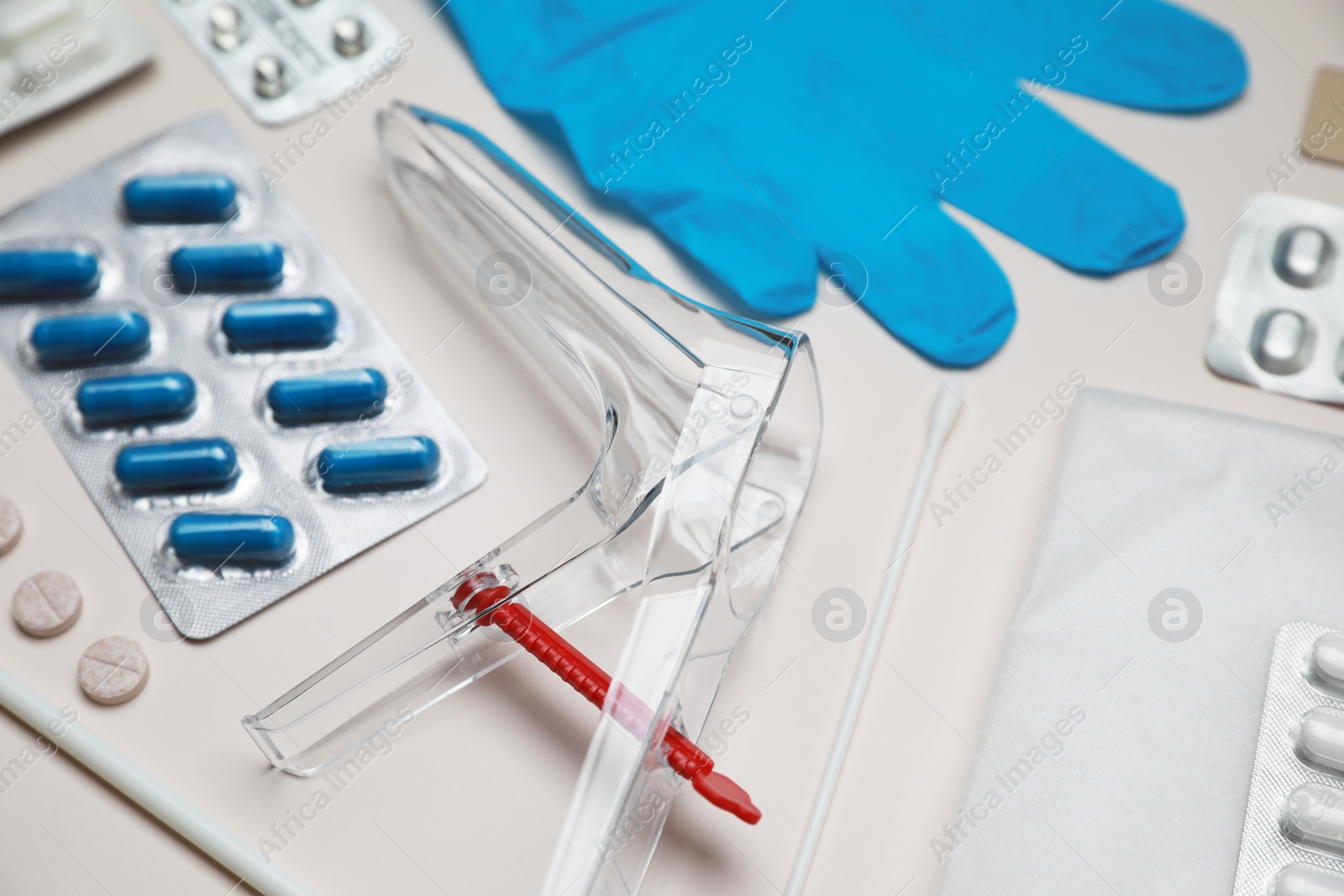 Photo of Sterile gynecological examination kit and pills on beige background