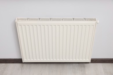 Photo of Modern radiator on white wall in room. Central heating system