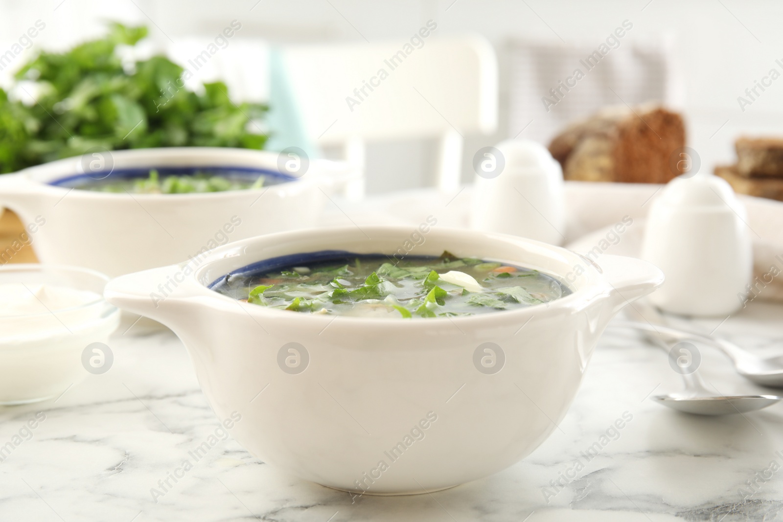 Photo of Delicious sorrel soup served on white marble table