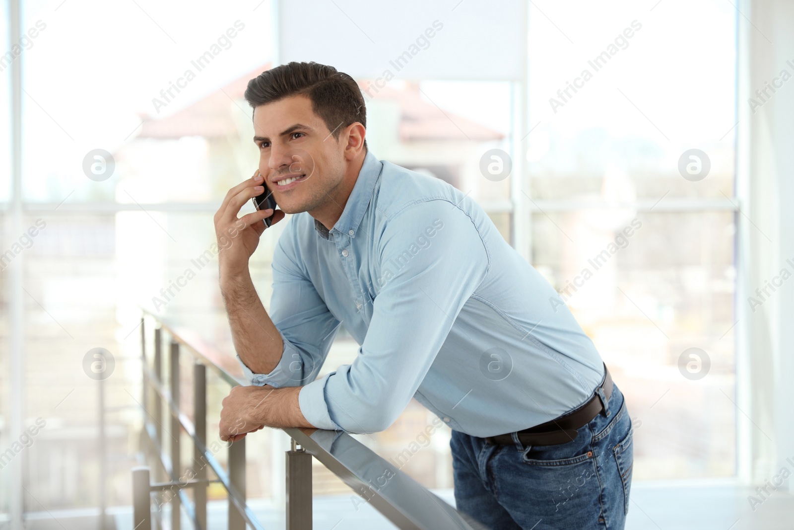 Photo of Portrait of handsome man talking on phone in light room