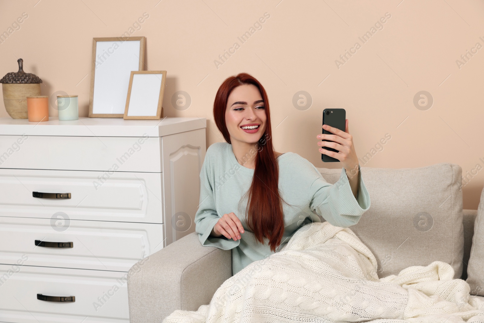 Photo of Happy woman with red dyed hair taking selfie at home