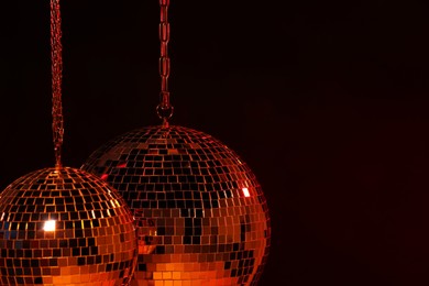 Photo of Shiny bright disco balls under red light, space for text