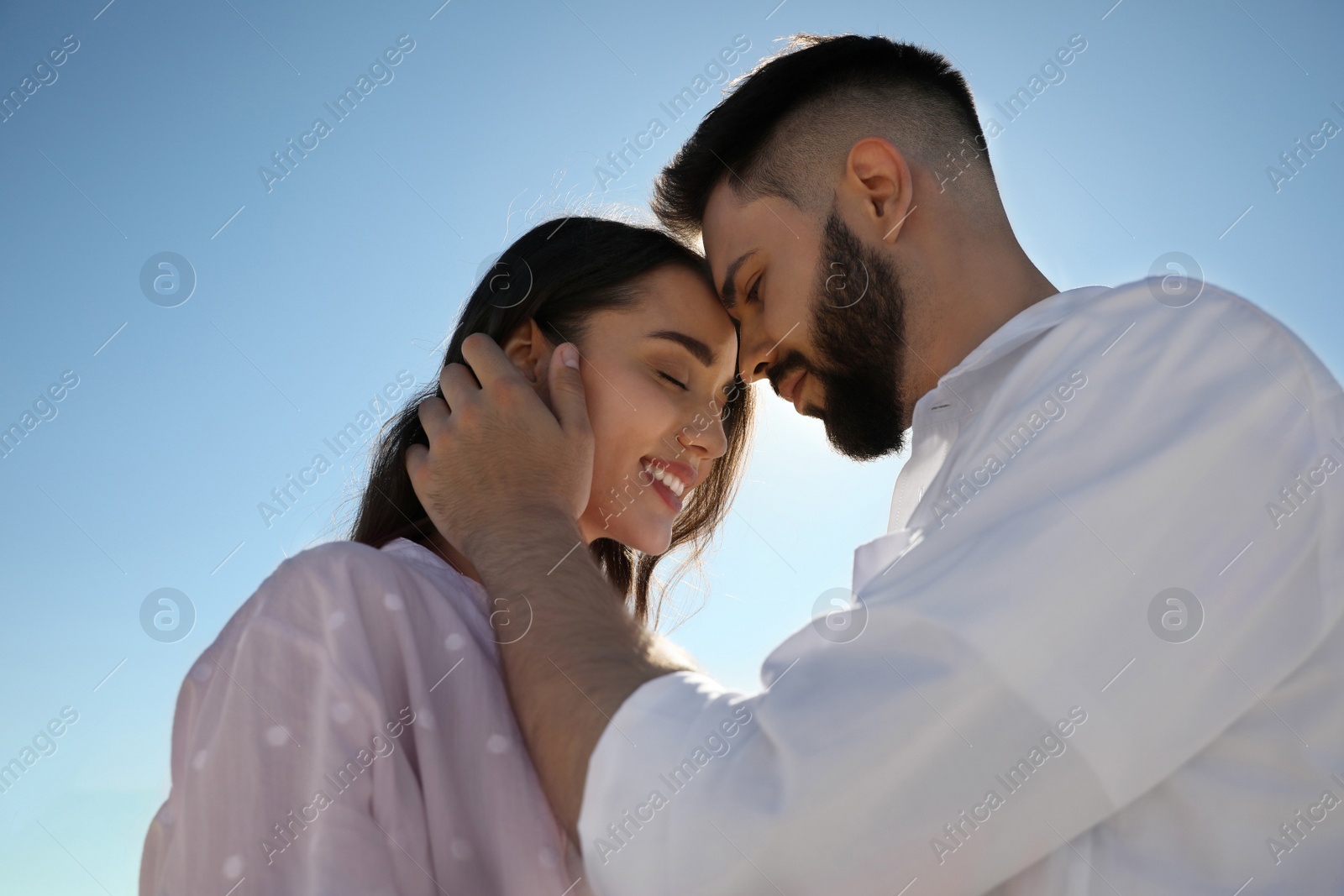 Photo of Happy young couple against blue sky, low angle view. Honeymoon trip