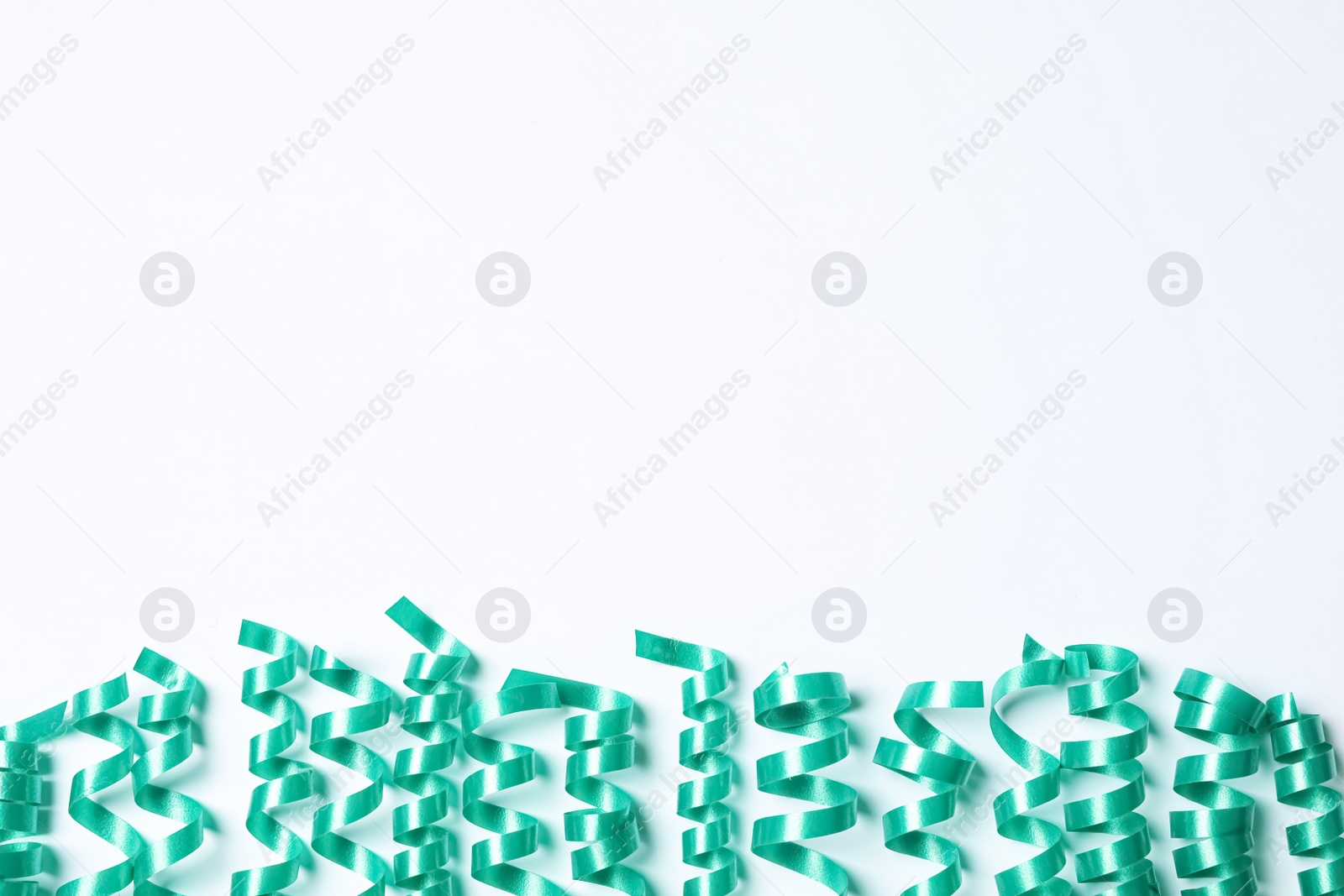 Photo of Turquoise serpentine streamers on white background, top view