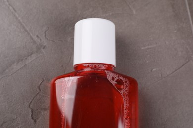 Photo of Fresh mouthwash in bottle on grey textured table, top view