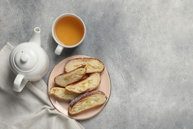 Pieces of delicious yeast dough cake and tea on light gray table, flat lay. Space for text