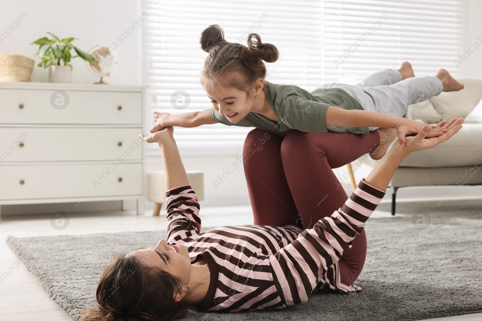 Photo of Young mother and her daughter having fun together at home