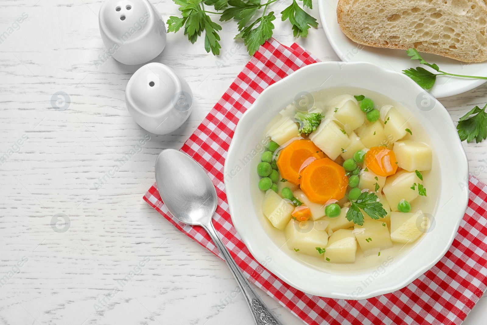 Photo of Bowl of fresh homemade vegetable soup served on white wooden table, flat lay. Space for text