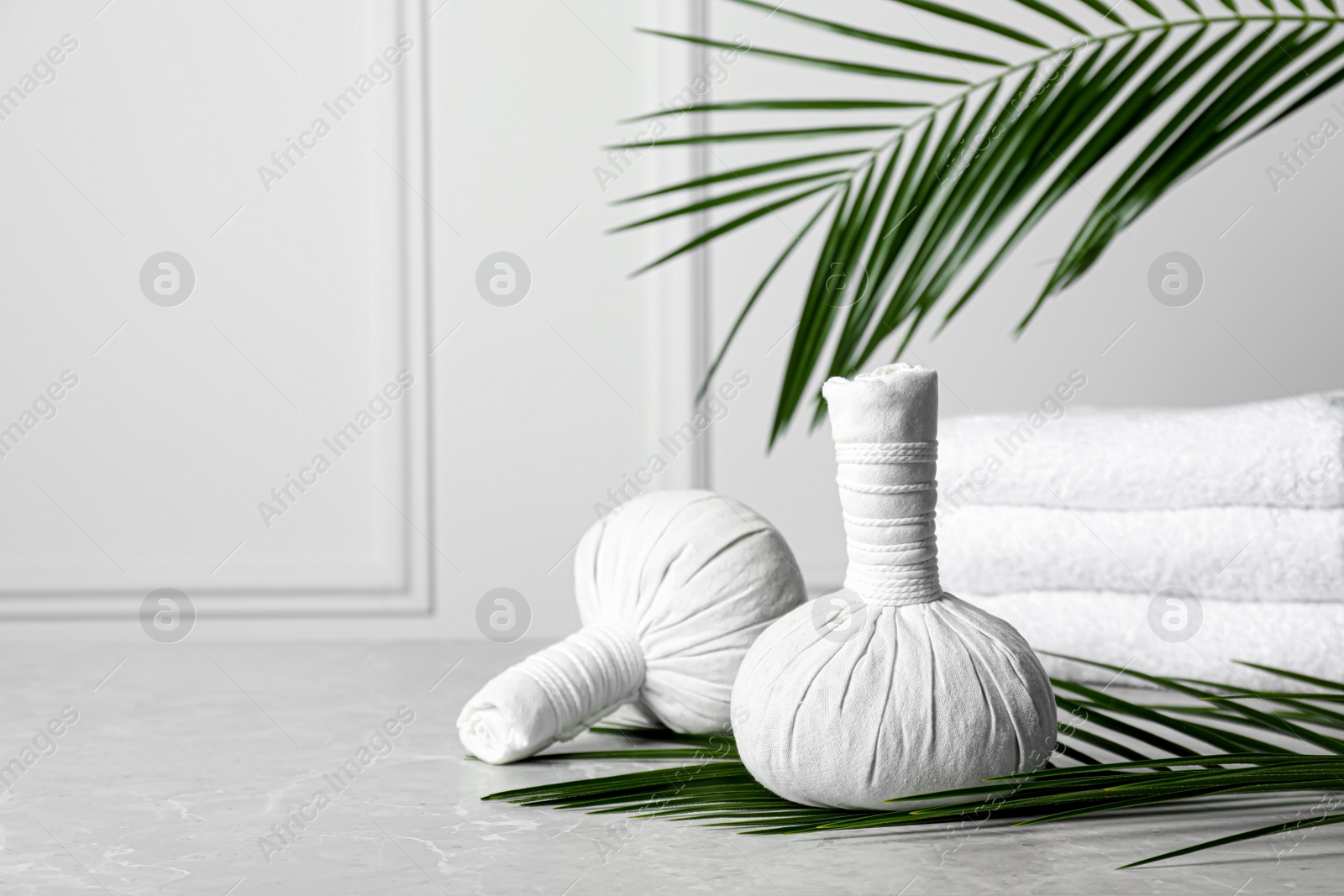 Photo of Spa bags and palm branches on light gray marble table, space for text