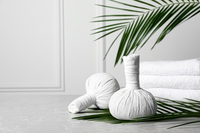 Photo of Spa bags and palm branches on light gray marble table, space for text