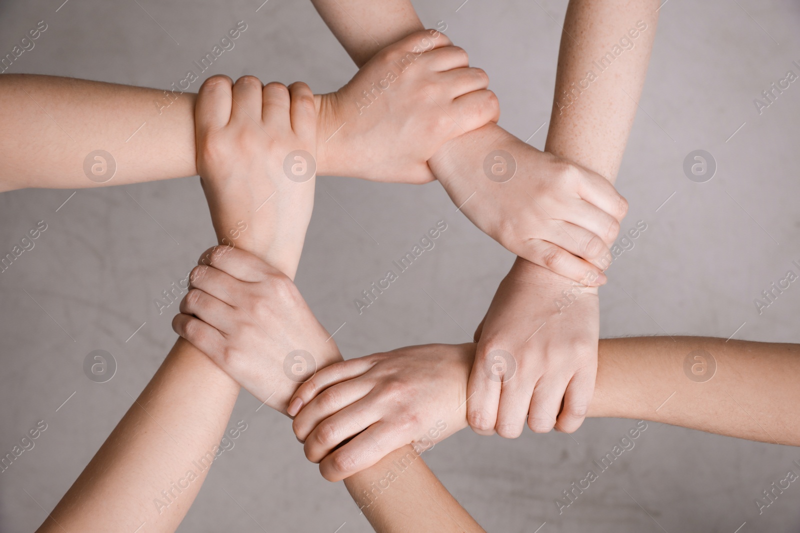 Photo of People holding hands together on grey background, top view. Responsibility concept