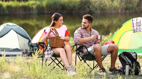Young couple having picnic near camping tent