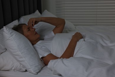 Woman suffering from headache in bed at night