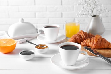 Photo of Cup of coffee, jam and croissants on white wooden table. Tasty breakfast