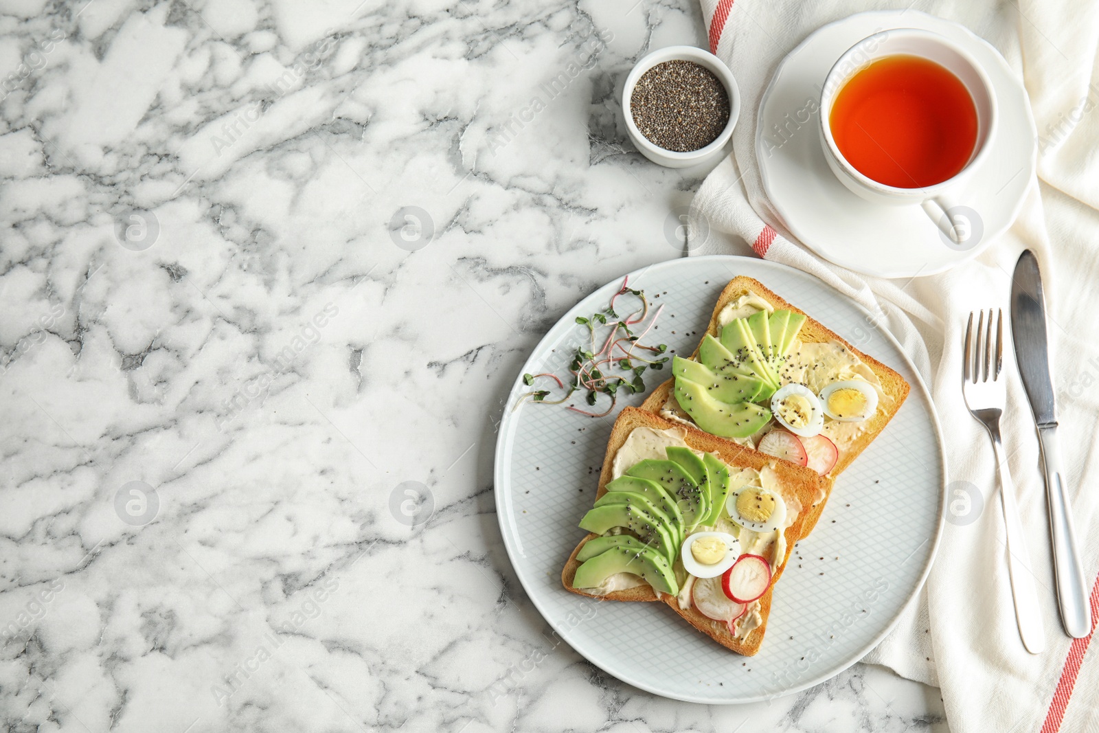 Photo of Plate of tasty toasts with avocado, quail eggs and chia seeds served on marble table, top view. Space for text