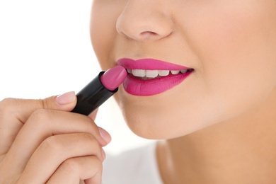 Beautiful woman applying lipstick on light background, closeup