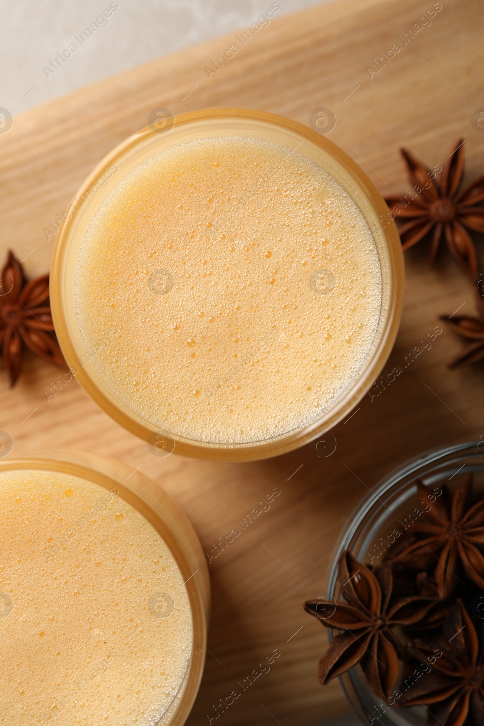Photo of Glasses of delicious eggnog with anise on grey marble table, top view