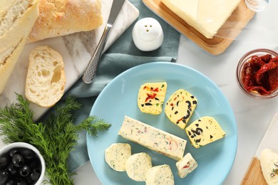 Photo of Different types of tasty butter served on white marble table, flat lay