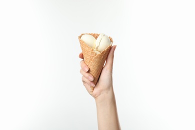 Woman holding delicious ice cream in waffle cone on white background, closeup