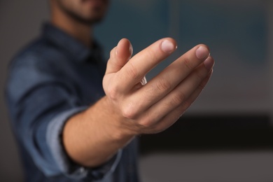 Man offering helping hand on blurred background, closeup