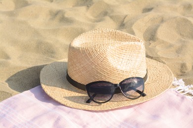 Photo of Hat with beautiful sunglasses on pink blanket