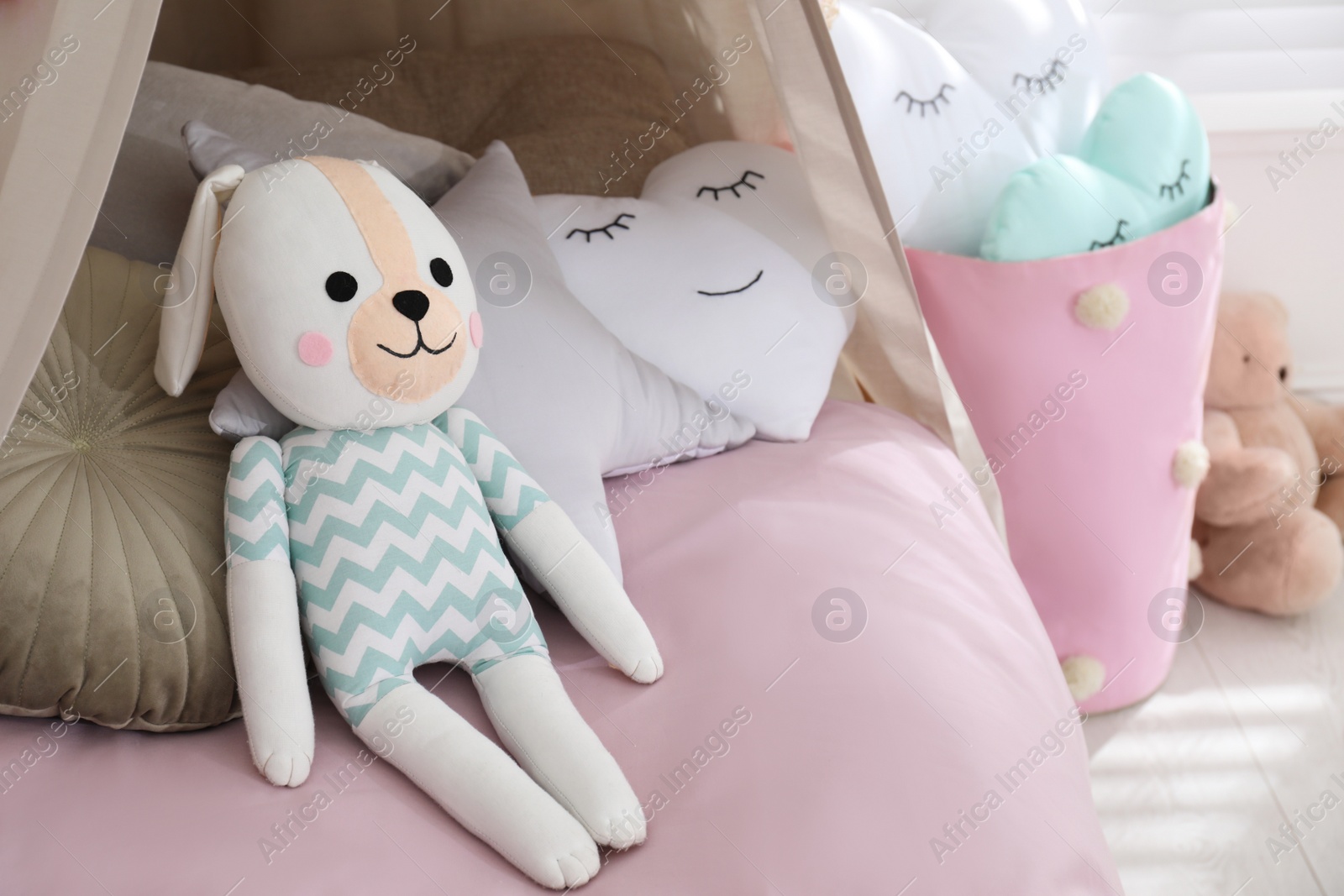 Photo of Cute toy bunny on bed in stylish playroom, space for text. Interior design