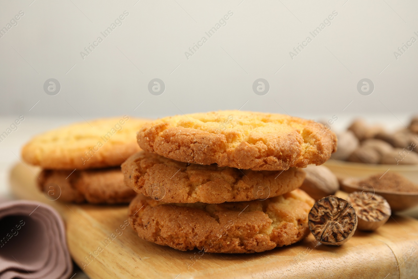 Photo of Nutmeg seeds and tasty cookies on wooden board, closeup